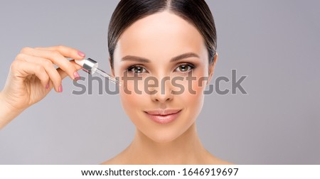 Skin care concept. Beauty portrait of smiling young woman girl holding pipette with cosmetic oil  or  serum near clean face. Cosmetology and Spa 商業照片 © 