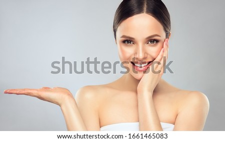 Beautiful woman with  clean fresh skin .Sweet smiling girl  expressive  pointing to the side . Presenting your product. . Expressive facial expressions.  Cosmetology , beauty  and spa .  Face care Stock foto © 