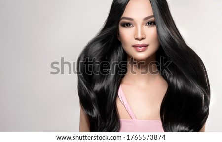 Beautiful asian model girl with shiny black and straight long hair . Keratin straightening . Treatment, care and spa procedures for hair . Chinese girl with smooth hairstyle