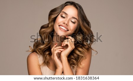 Beautiful smiling woman holding hands near face. Beauty girl  with curly hair   . Presenting your product. Expressive facial expressions . Wavy hairstyle