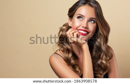 Happy and surprised girl  smiling  looking to the side presenting  your product . Beautiful curly hair woman amazed ,   with red nails manicure. Expressive facial expressions. Pin up