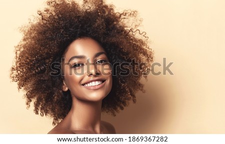 Beauty portrait of african american girl with clean healthy skin on beige background. Smiling dreamy beautiful black woman.Curly hair in afro style Foto stock © 