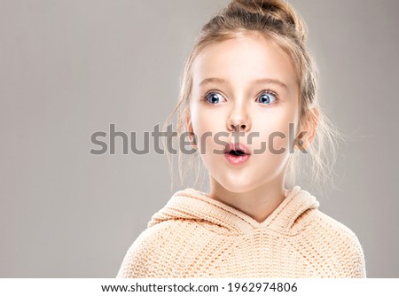 The child is a beautiful girl with wide eyes, look away in surprise. Baby in a knitted sweatshirt . Children's products , clothing and accessories . Expressive facial emotions