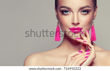 Beautiful model girl with pink fuchsia manicure on nails . Fashion makeup and cosmetics . Large earrings tassels jewelry Magenta color . Foto stock © 