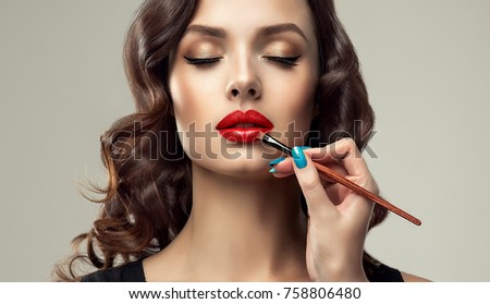  Makeup artist applies  red lipstick  . Beautiful woman face. Hand of make-up master, painting lips of young beauty  model girl . Make up in process
 Stock foto © 