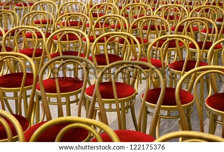 Chairs in the hall. Hall interior. Many red chairs with golden frames in big hall, not clear, background, pattern.