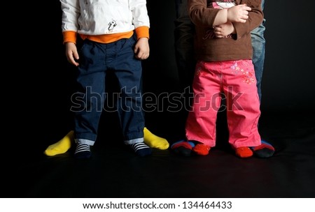 Four people family legs feet in colorful stripy socks standing together on black background, pretty woman,man,boy and small girl legs in colourful socks on dark backgrounds,family close up