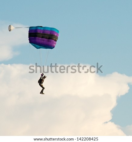 One parachute, landing parachutist, Skydiver with parachute open landing, Paragliding over the clouds against blue sky Paraglider flying in the blue sky with clouds backgrounds,sunset, Lithuania,sport