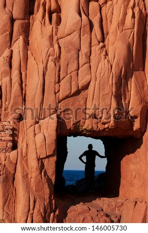 Red Rock fragment in Sardinia in Arbatax, man in the Red Rock in Arbatax, Sardinia, Italy, Red Rock pattern and structure close up, male and Red Rock, man looking to the sea in Red Rock, Arbatax