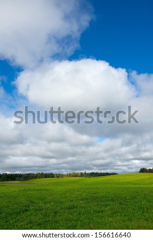 Landscape with cloudy sky background.Big cloudy sky background,Lithuania.Lithuanian nature with green grass field and big blue sky background, summer time. Lithuanian nature.Dramatic autumn background