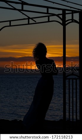 Woman silhouette in golden sunset with the sea background, dramatic sunset and alone woman, romantic mood, single alone woman in romantic atmosphere, romantic sunset,  woman in asia, summer holidays
