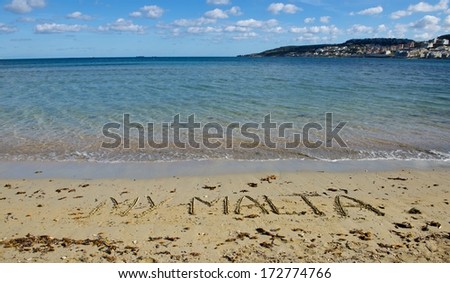 Sunny day in Melieha Bay in Malta with the letters in the sand, maltese coastline and writing on the sand My Malta. Malta. My Malta. Writing on the sand. Holidays in Malta