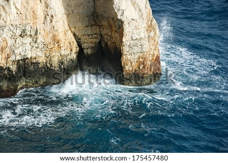 Wave breaking on the rocks in the sea, Blue Grotto rock fragment view in Malta close up, rock and water, Blue Grotto, view to the rock from the sea, popular place in Malta,crystal sea water, nature