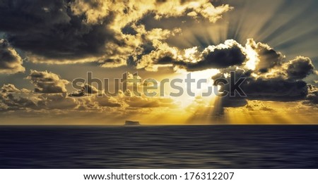 Amazing sunset with clouds formation and blur sea background, Filfla island view in Malta on dramatic sunset light, maltese landscape, dramatic sunset in ocean