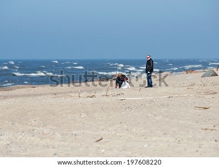 KARKLE, LITHUANIA - MARCH 8: couple of people collecting rubbish near the sea, social life, environment scene on March 8, 2014. Social activity. People responsible for environment, enviroment theme
