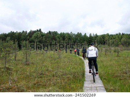 Young group riding bicycles by dirty road in countryside,group cyclists on a way between trees,young cyclists touring in Lithuania,bicycle in Lithuania, cycling bicycle,summer activities in Lithuania