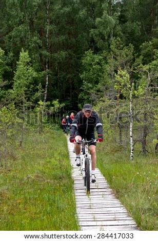 Varnikai, Lithuania-Sep 6:group of people riding bicycles by dirty road in Vawnikai regional park, Lithuania on Sep 6,2014,group cyclists traveling in lithuanian nature, tour by bicycle in Lithuania