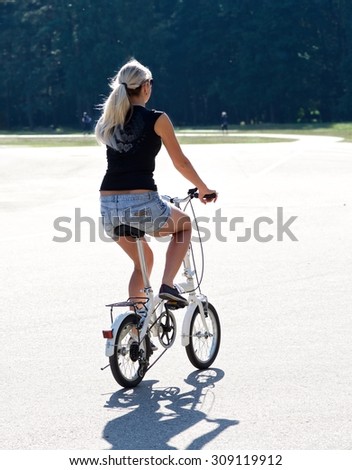 Middle age woman riding bicycle by dirty road in the park with blurry forest background,woman cyclist training in the park in Vilnius, Lithuania,summer sport activities
