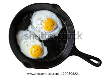 Two fried eggs in cast iron frying pan sprinkled with ground black pepper. Isolated on white from above. 商業照片 © 