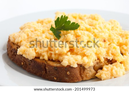 Scrambled eggs on multi-grain brown toast garnished with parsley.