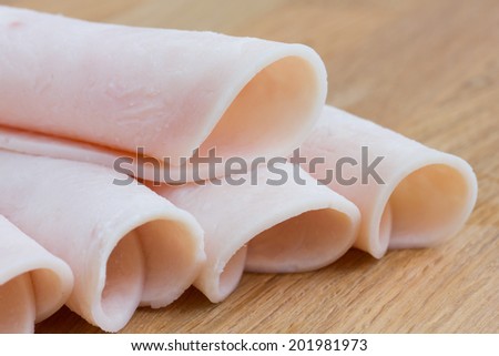 Rolled slices of ham on a wood surface.