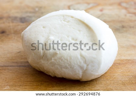 Single ball of mozzarella cheese on rustic wood surface.