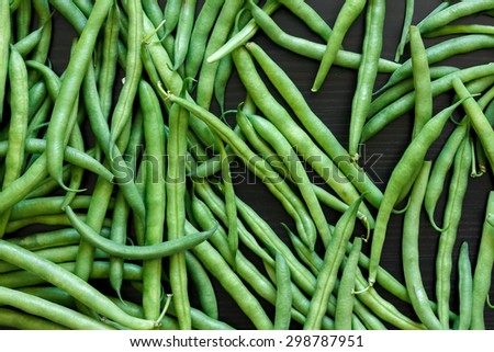 Whole French green string beans  on black rustic surface.