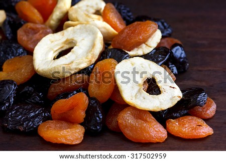 Pile of mixed dried fruit on dark wood. In perspective with space for text.