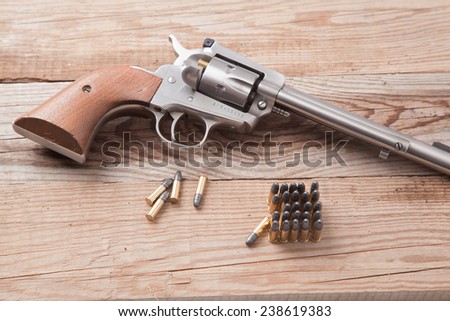 A pistol with bullets on a wooden background.