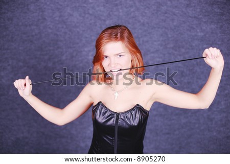 Dangerous girl holds knout, she has leather dress