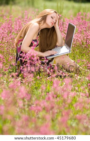 Girl works with wi-fi solution in beautifl meadow full of flowers