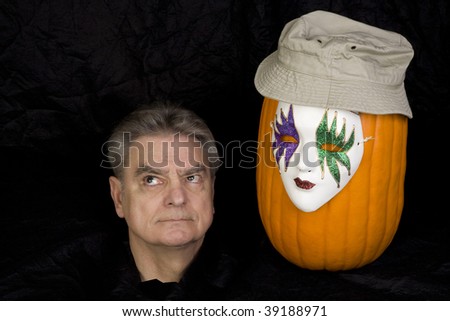 Human head and a pumpkin wearing a hat and a mask.