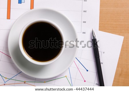 Cup of strong coffee over business diagrams, closeup soft focus photo