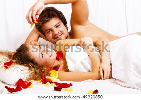 Beautiful couple in rose petals in bedroom