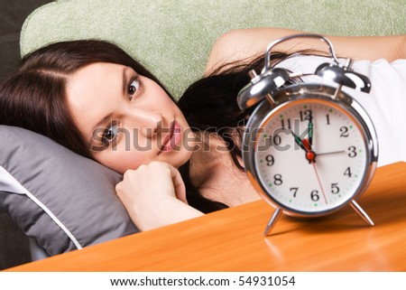 Vintage alarm clock, with beautiful young woman sleeping in the background