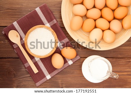 Eggs, milk and flour on a wooden table