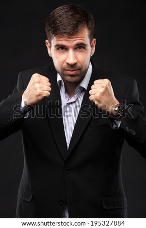 Young businessman in a black suit on dark background