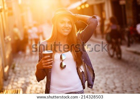 Young stylish woman drinking coffee to go in a city street