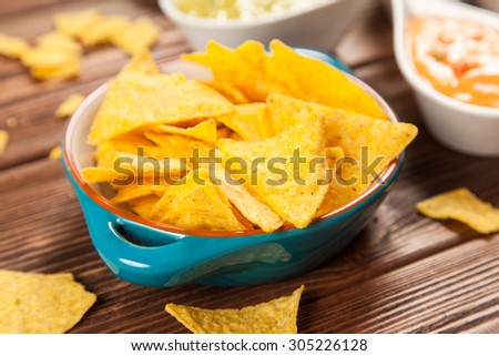Plate of nachos with salsa, cheese and guacamole dips