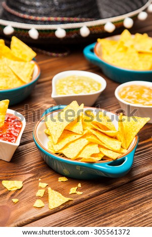 Plate of nachos with salsa, cheese and guacamole dips