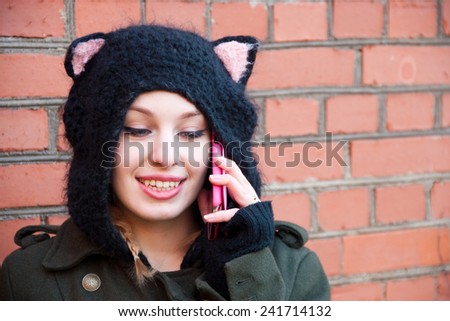 Young woman in a funny knitted hat talking on mobile phone on the street