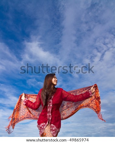 Happiness pretty girl in red plays with sarong during blue sky