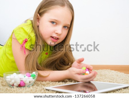 Portrait of a cute girl with tablet PC and colored candies