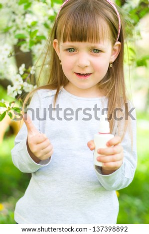 Portrait of a happy girl holding nasal spray,showing thumbs up outdoors