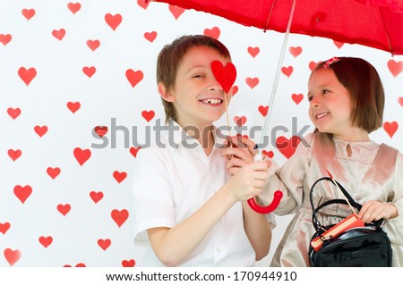 Love story.Children couple under red umbrella on hearts shapes rainy background for Valentine\'s Day and other occasions