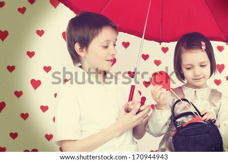 children couple under red umbrella on hearts shapes rainy background for Valentine\'s Day and other occasions