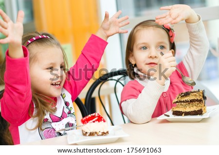 Cute little girls are eating cake in parlor
