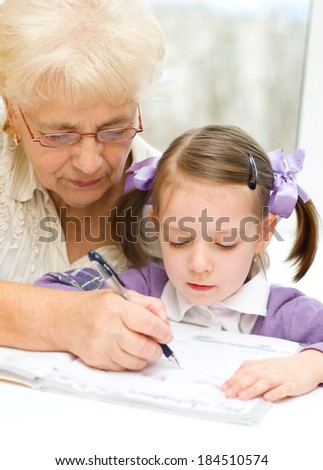 Grandmother teaches to write letters her granddaughter