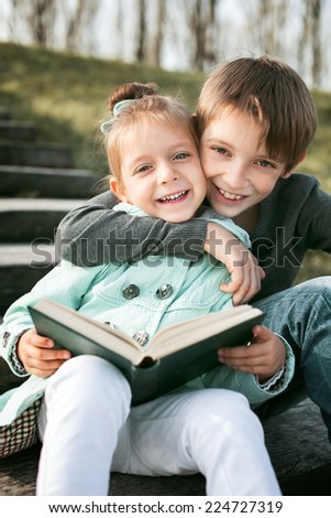 Kids reading together enjoying a book outdoors