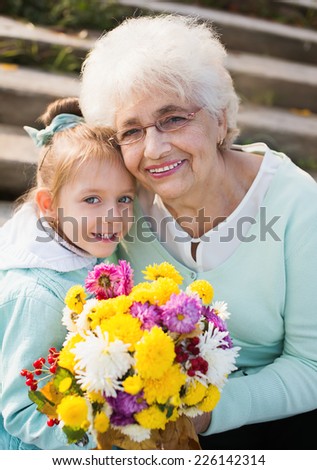 Grandmother with granddaughter holding flowers in the park